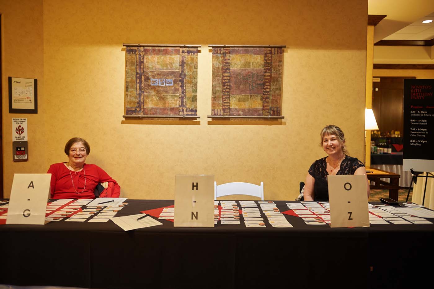 two people standing at a sign-in table sorted alphabetically