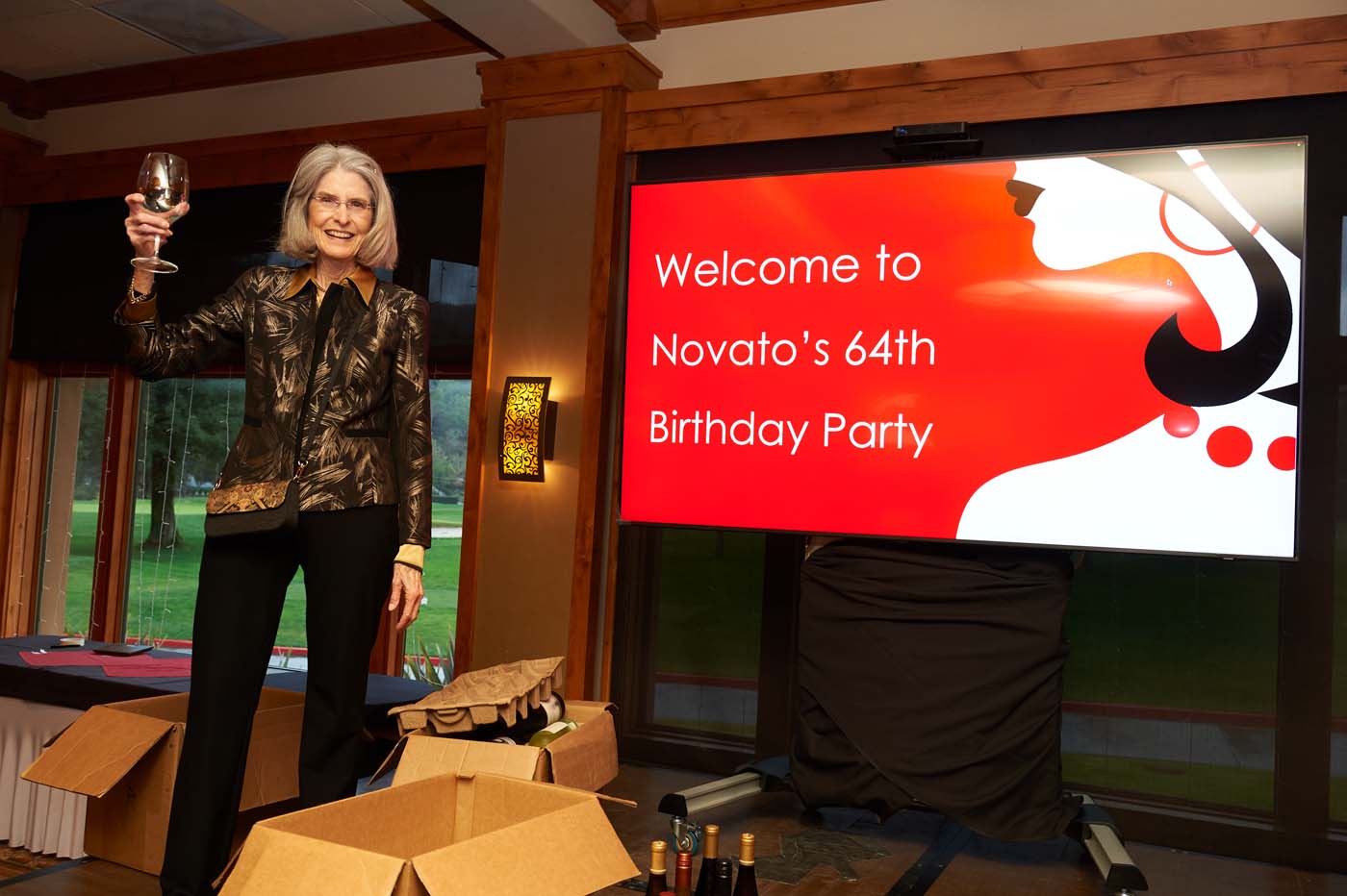 a woman making a toast in front of a sign that read 