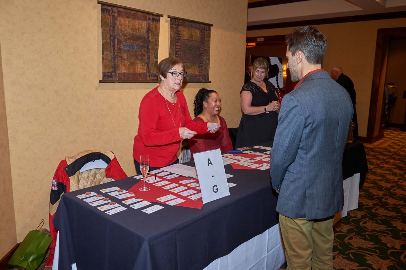 people standing in front of a sign-in name tag table
