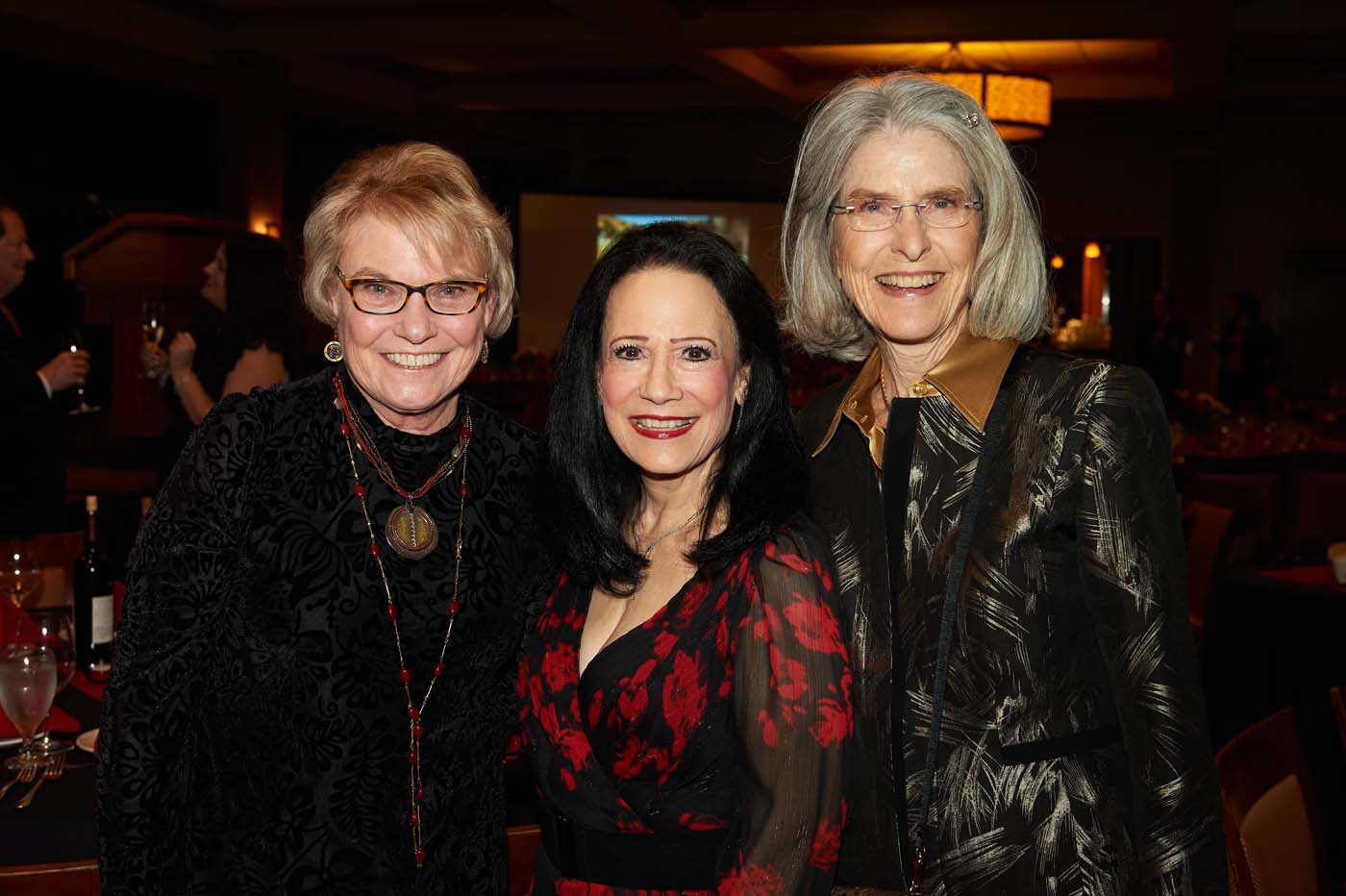 a group of three women standing and smiling together
