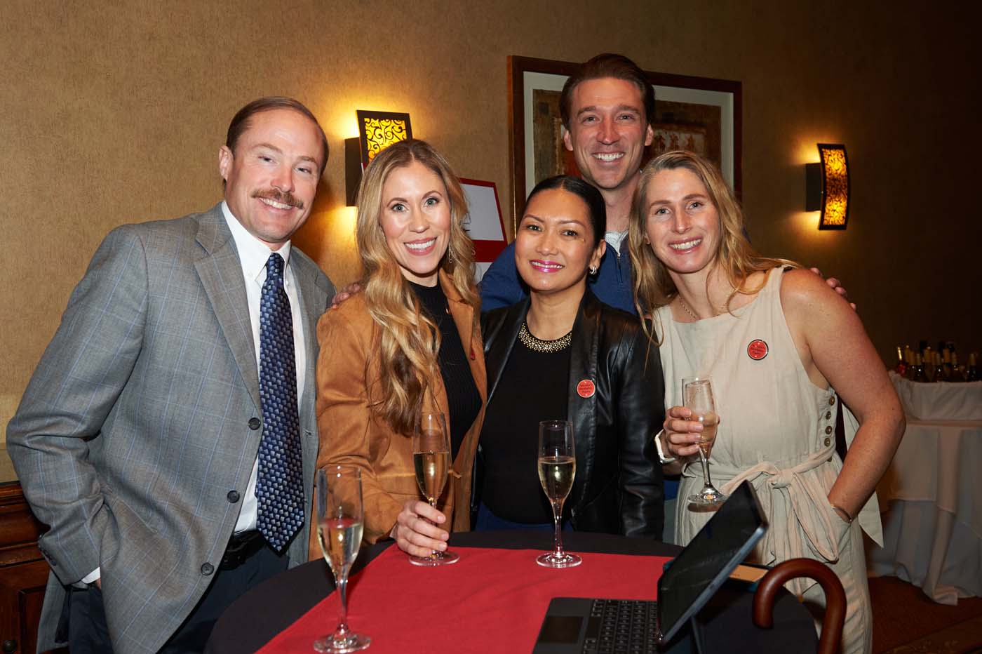 a group of five people standing and smiling together