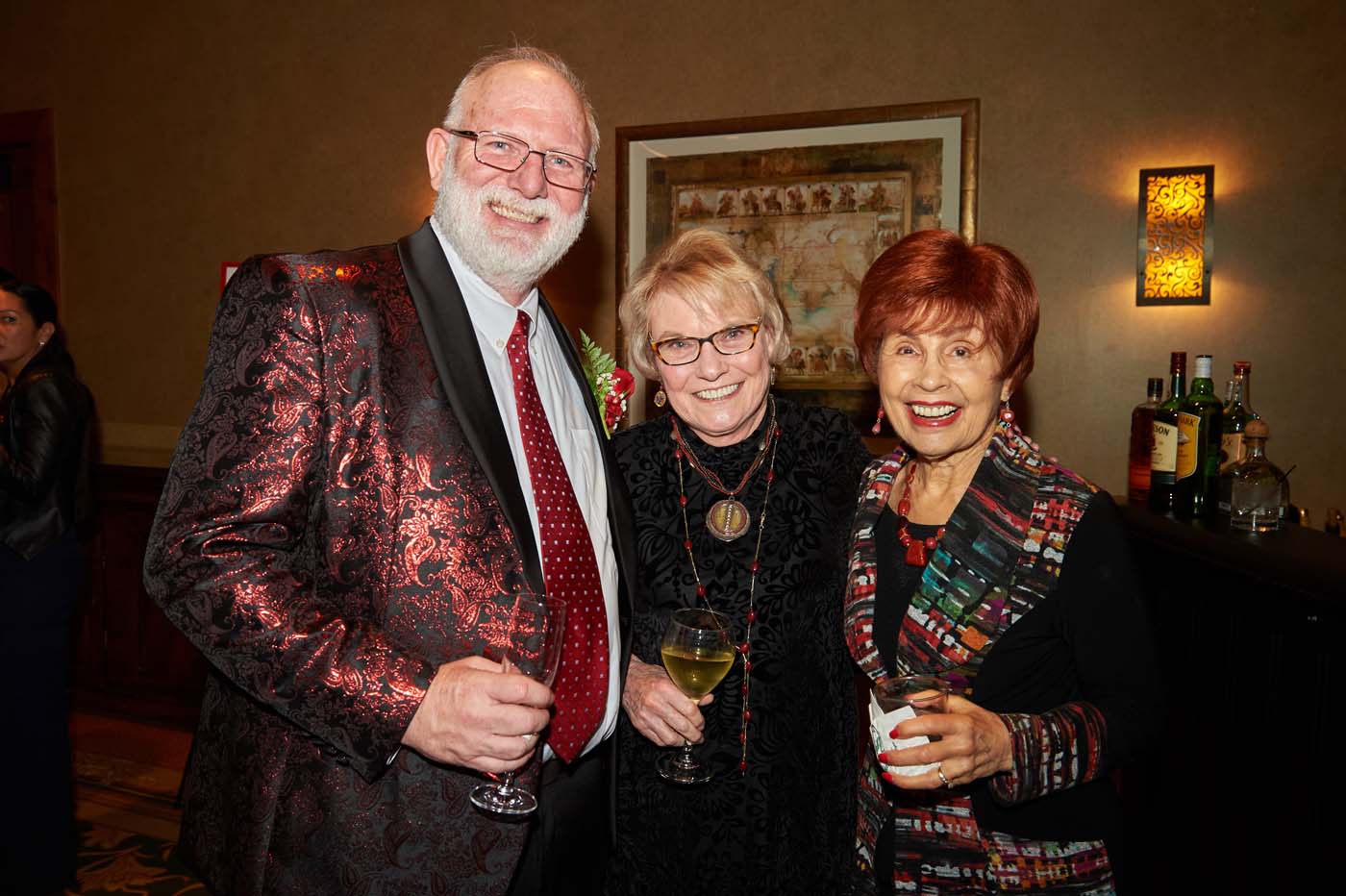 a group of three people standing and smiling together