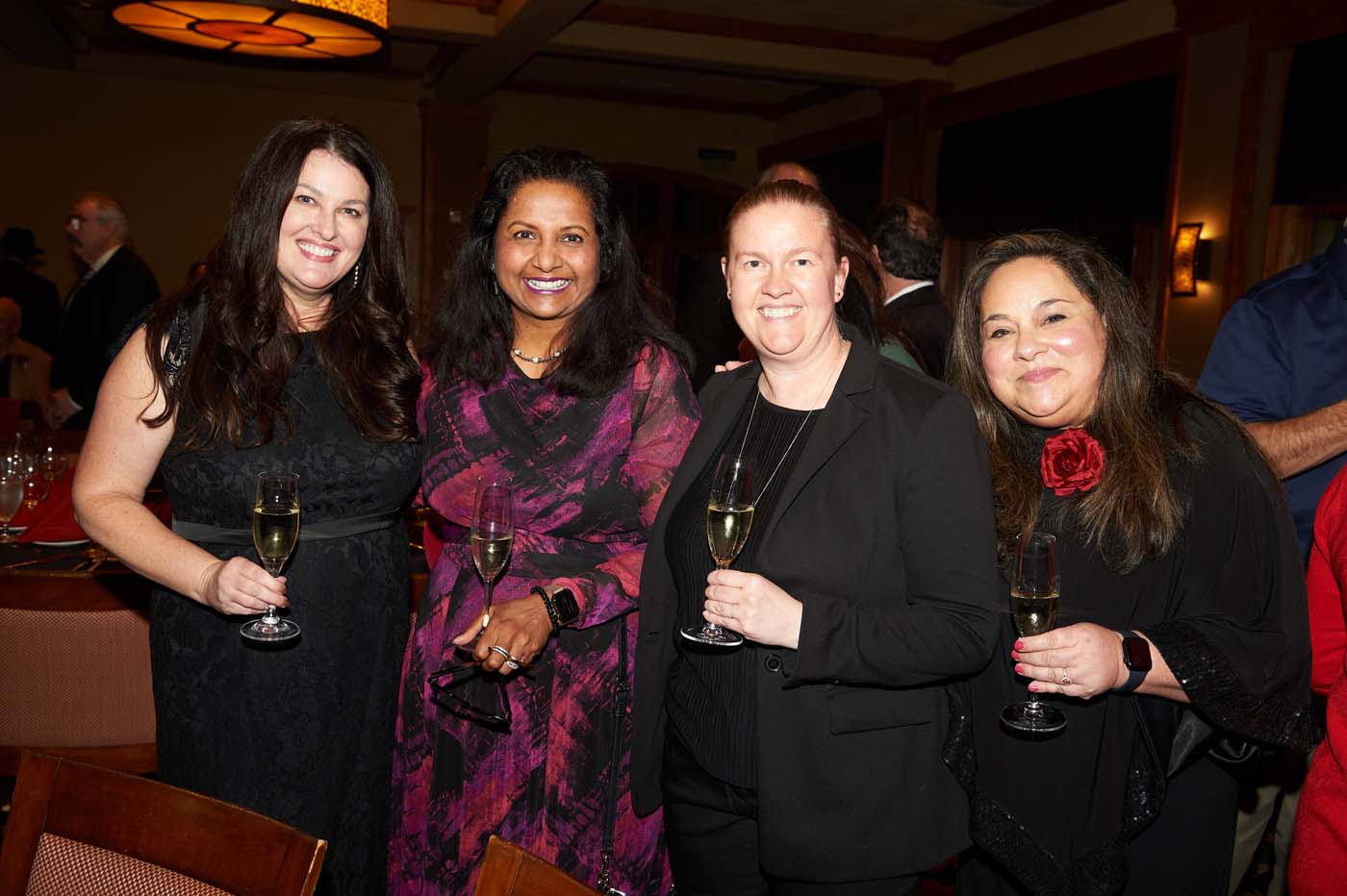 a group of four women standing and smiling together