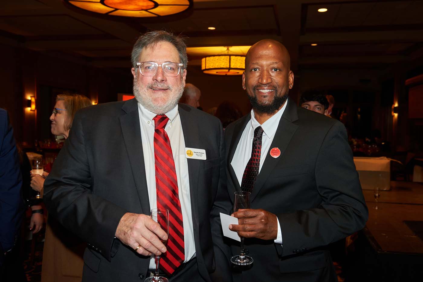 two men in suits standing together holding champagne flutes