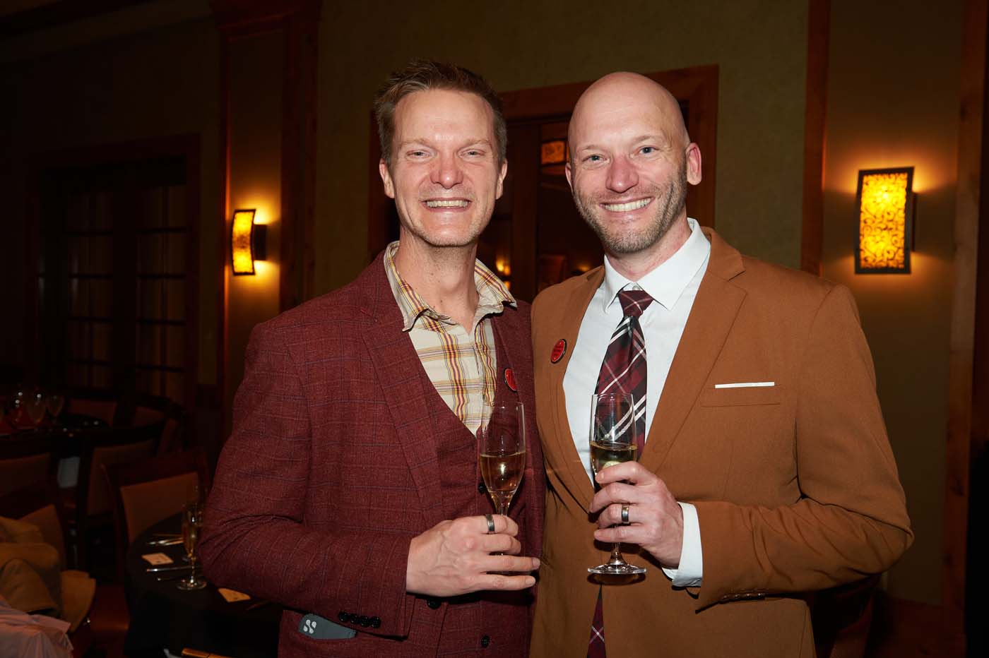 two men standing together and holding champagne flutes