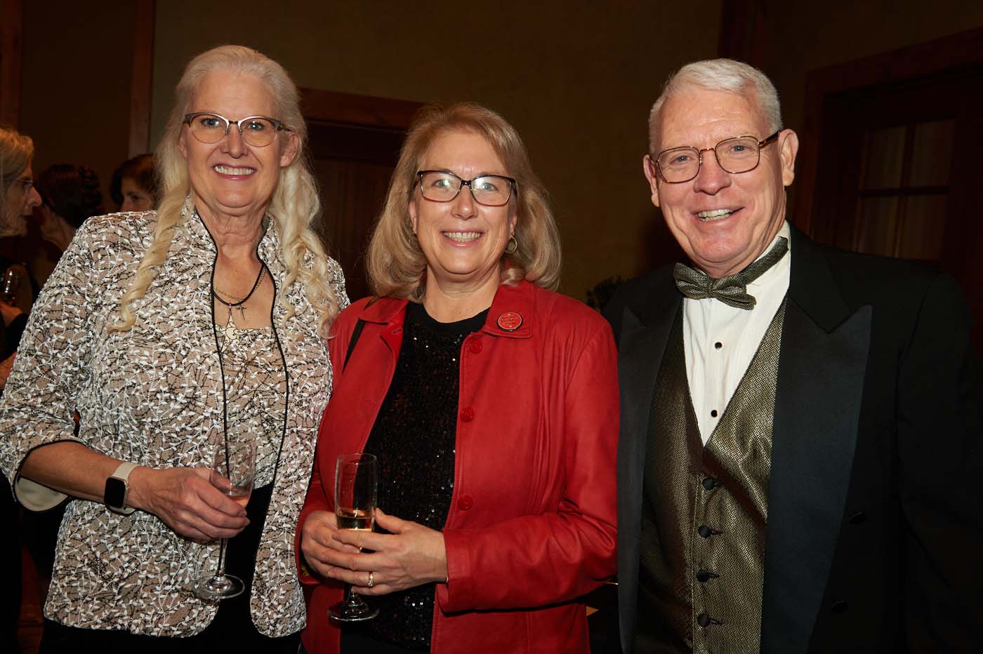 a group of three people standing and smiling together