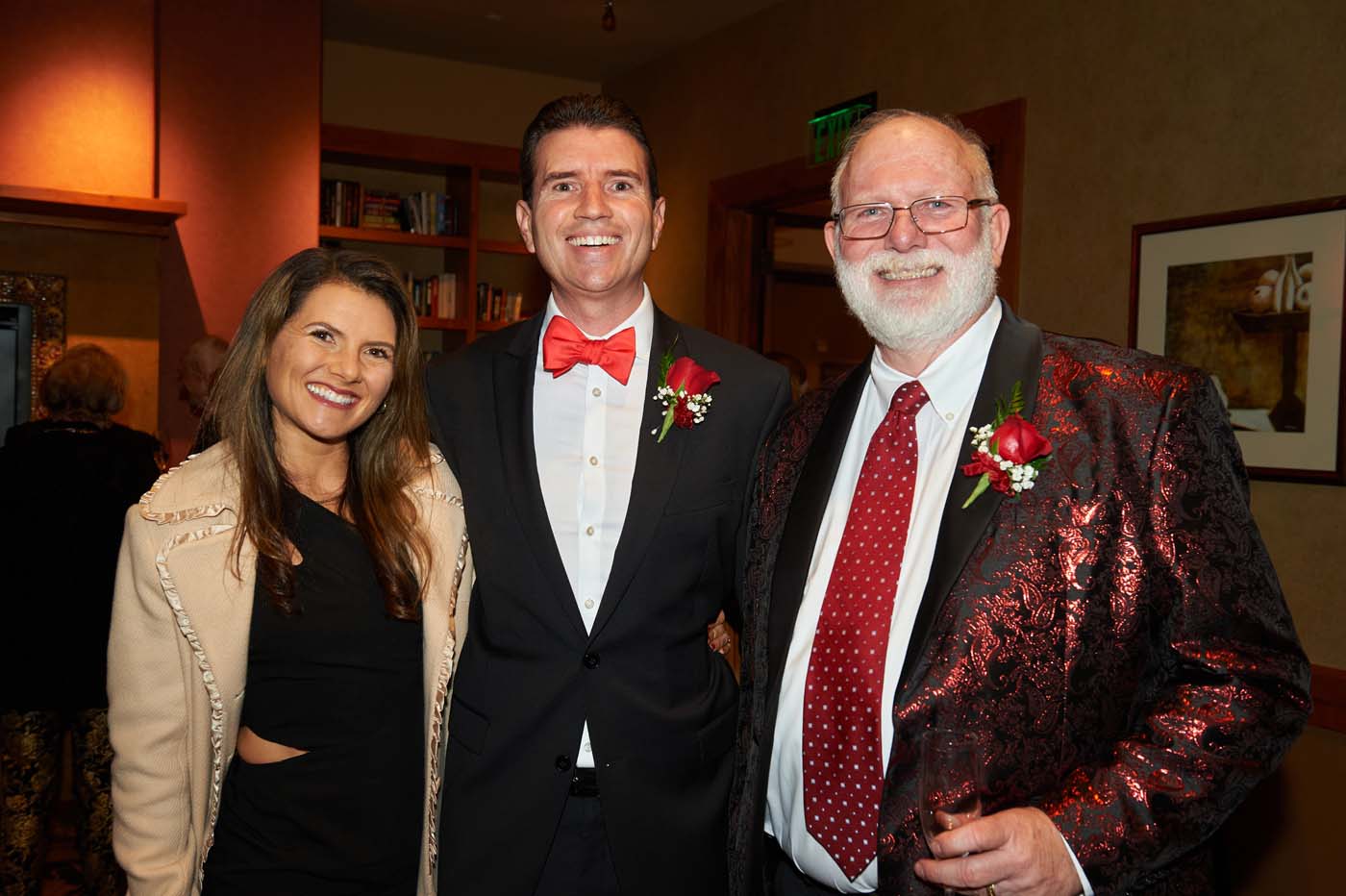 a group of three people standing and smiling together