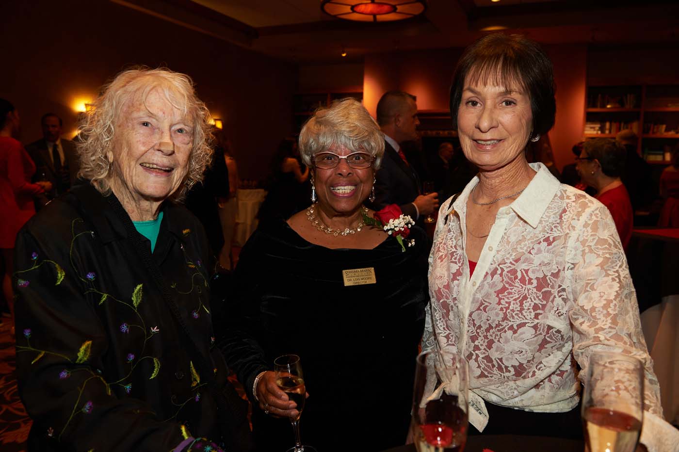 a group of three women standing and smiling together