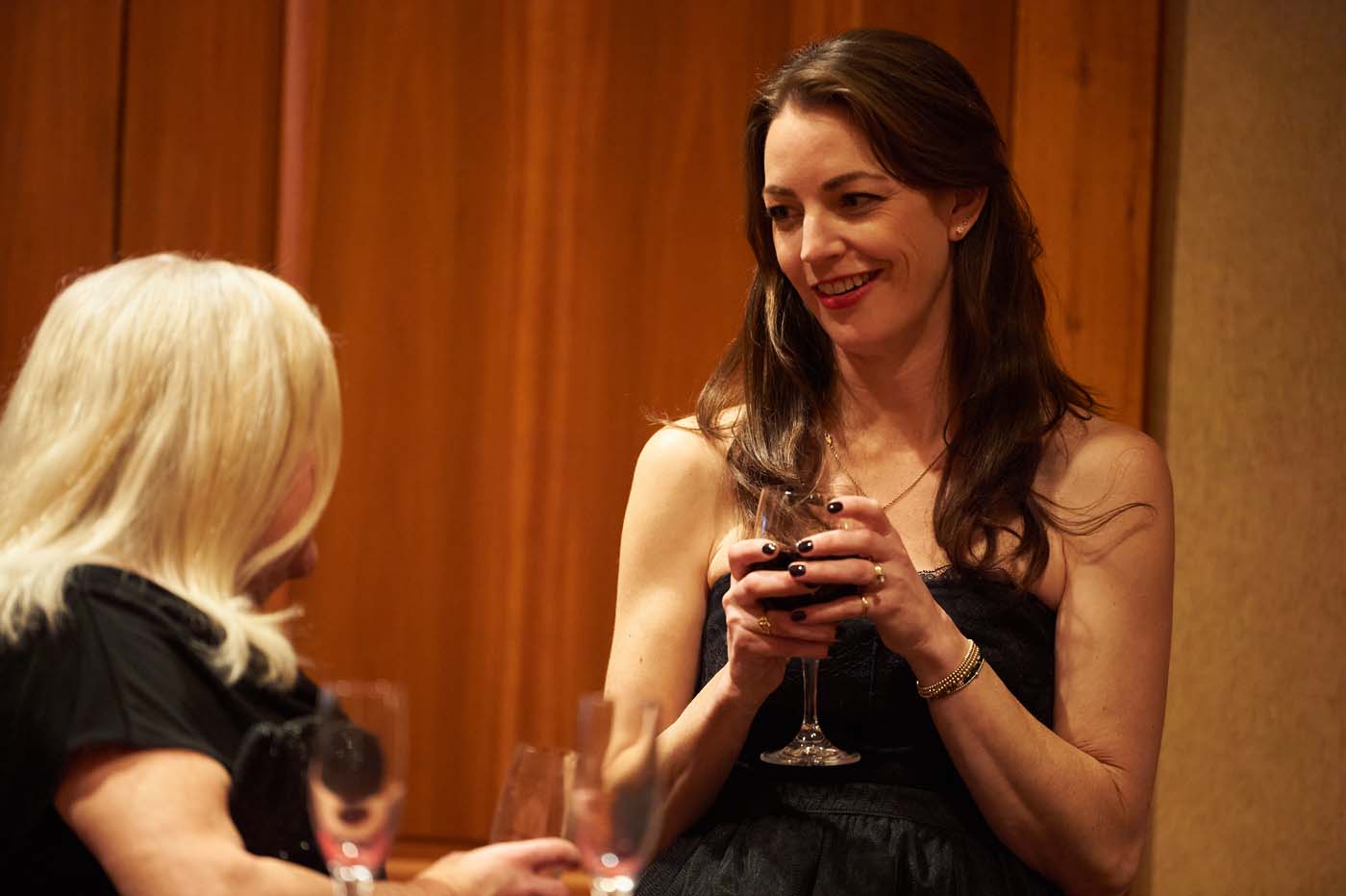 two women talking and holding wine glasses
