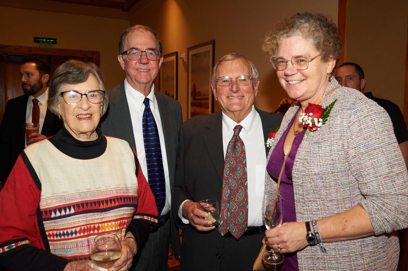 a group of four people standing and smiling together
