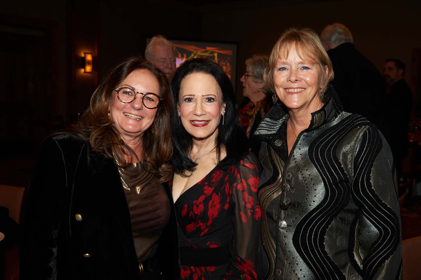 three women standing and smiling together