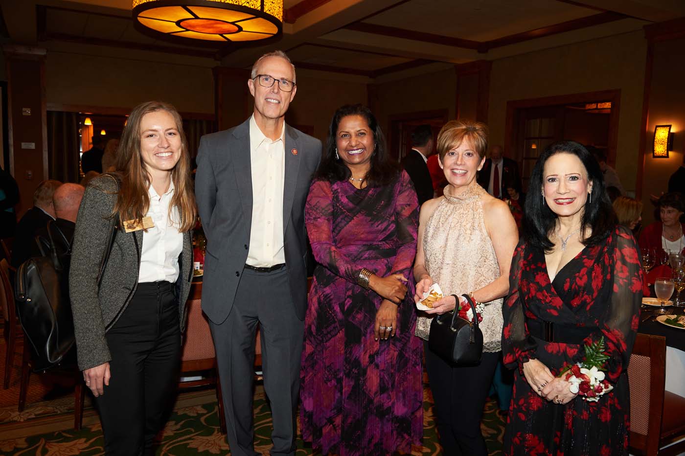 a group of five people standing and smiling together