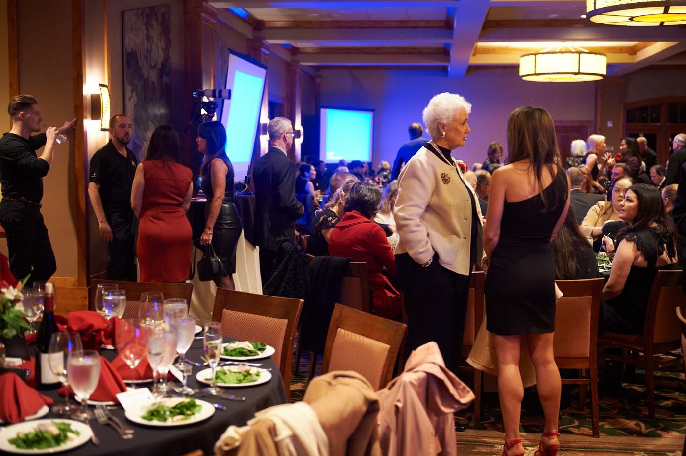 a crowded event room with tables and people gathered around