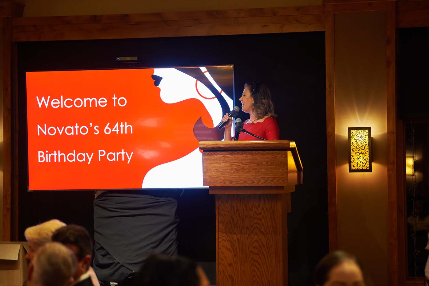 a woman at a podium with a microphone in front of a sign that reads 