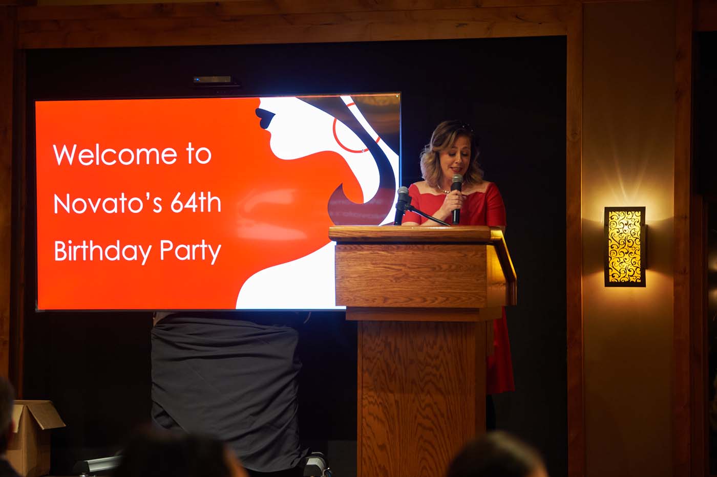 a woman at a podium with a microphone in front of a sign that reads 