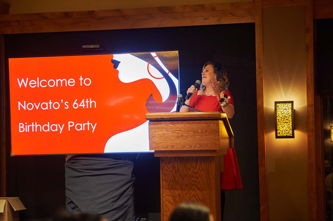 a woman at a podium with a microphone in front of a sign that reads 