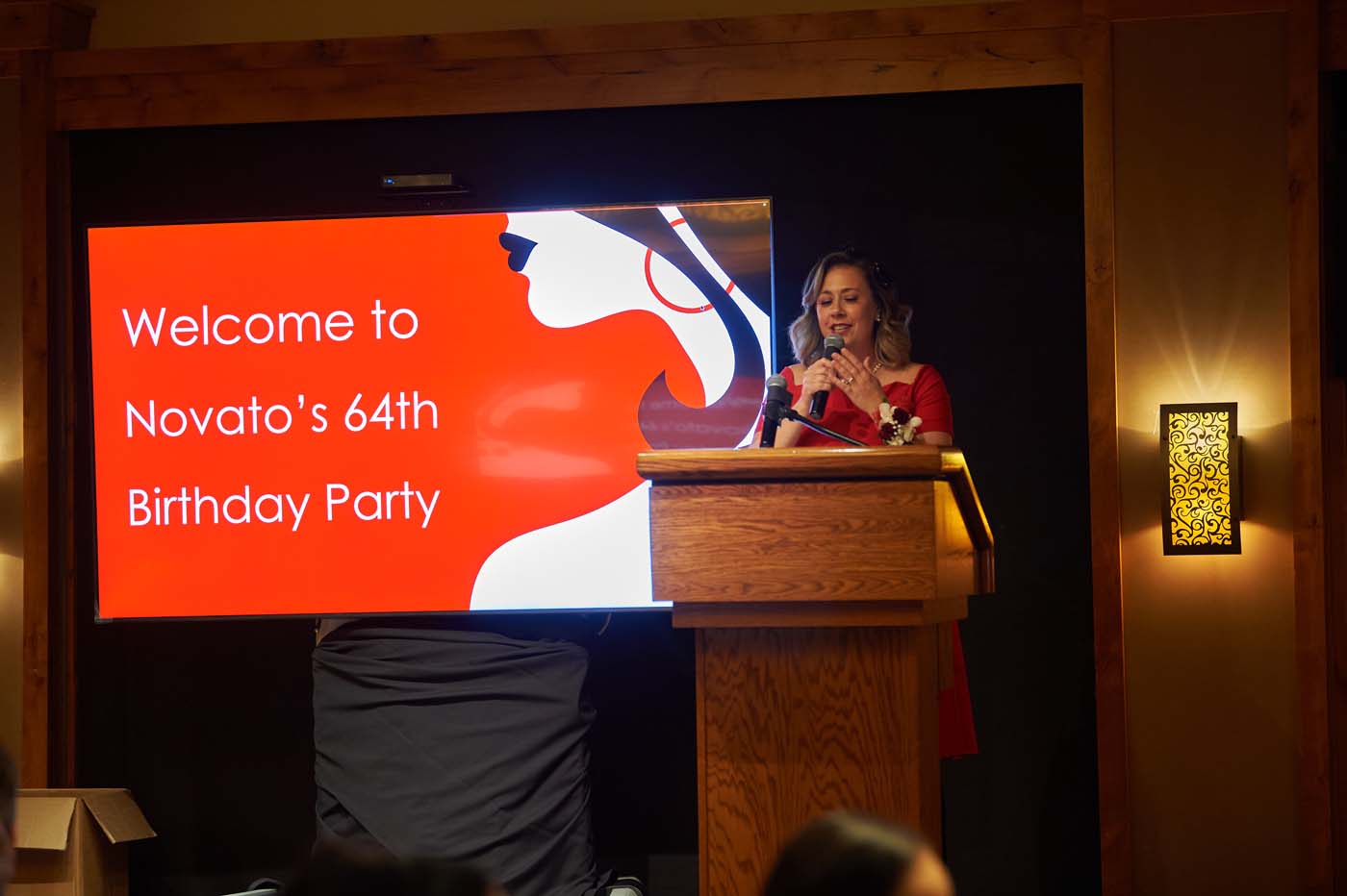 a woman at a podium with a microphone in front of a sign that reads 