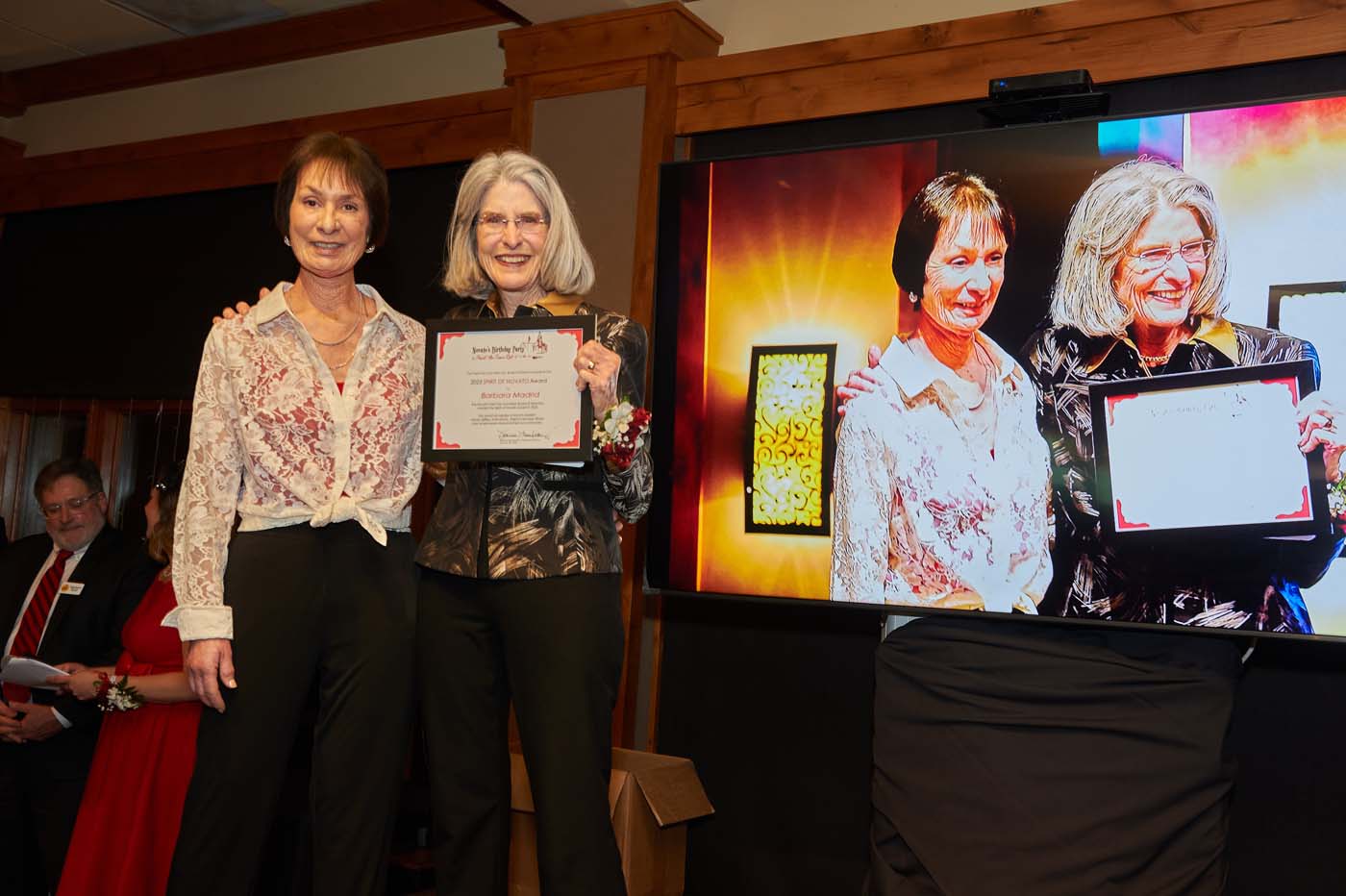 two women standing on a stage accepting an award