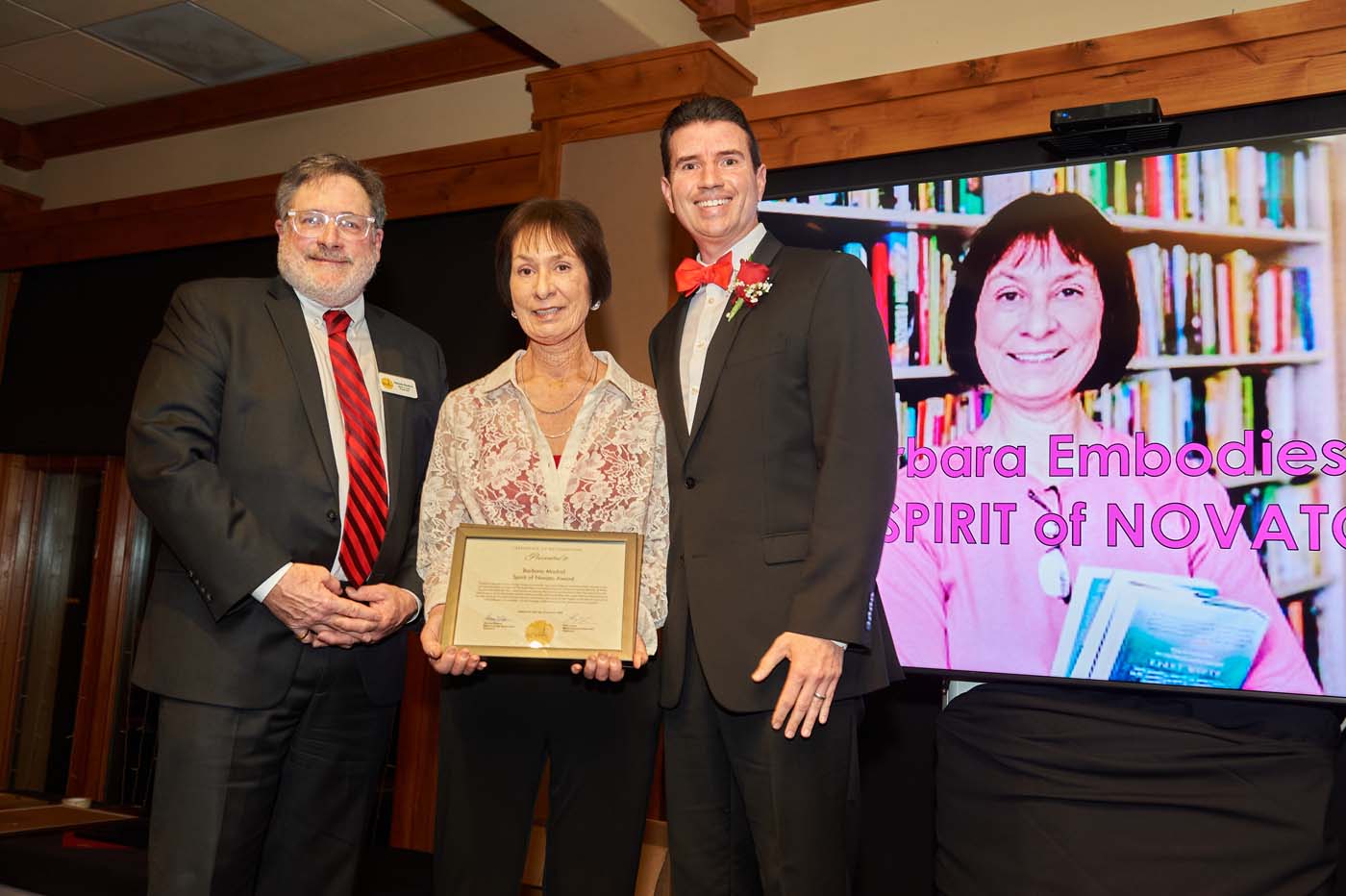 three people standing on a stage accepting an award