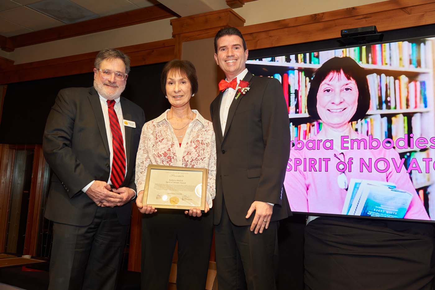three people standing on a stage accepting an award