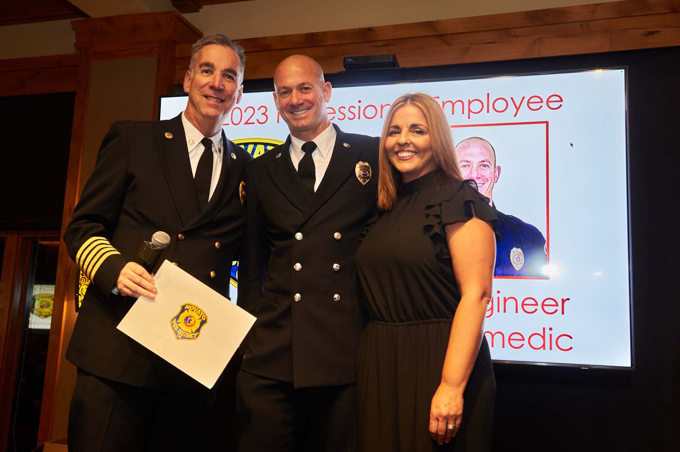 three people standing on a stage accepting an award