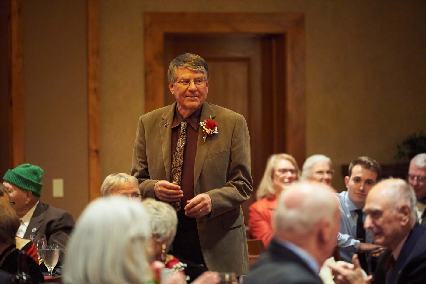 a man standing in a crowded room while other people clap