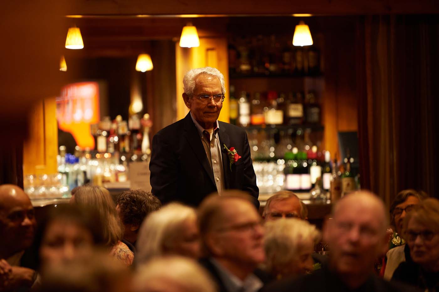 a man in a suit, standing in a crowded room