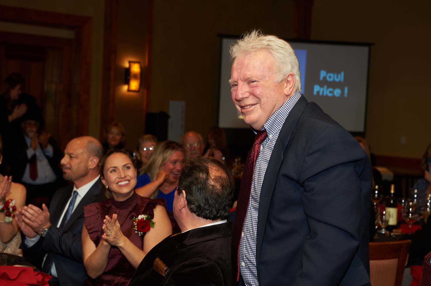 a man walking through a crowded event room smiling