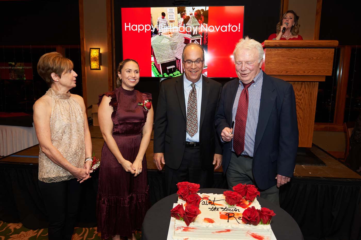 four people smiling after cutting a cake