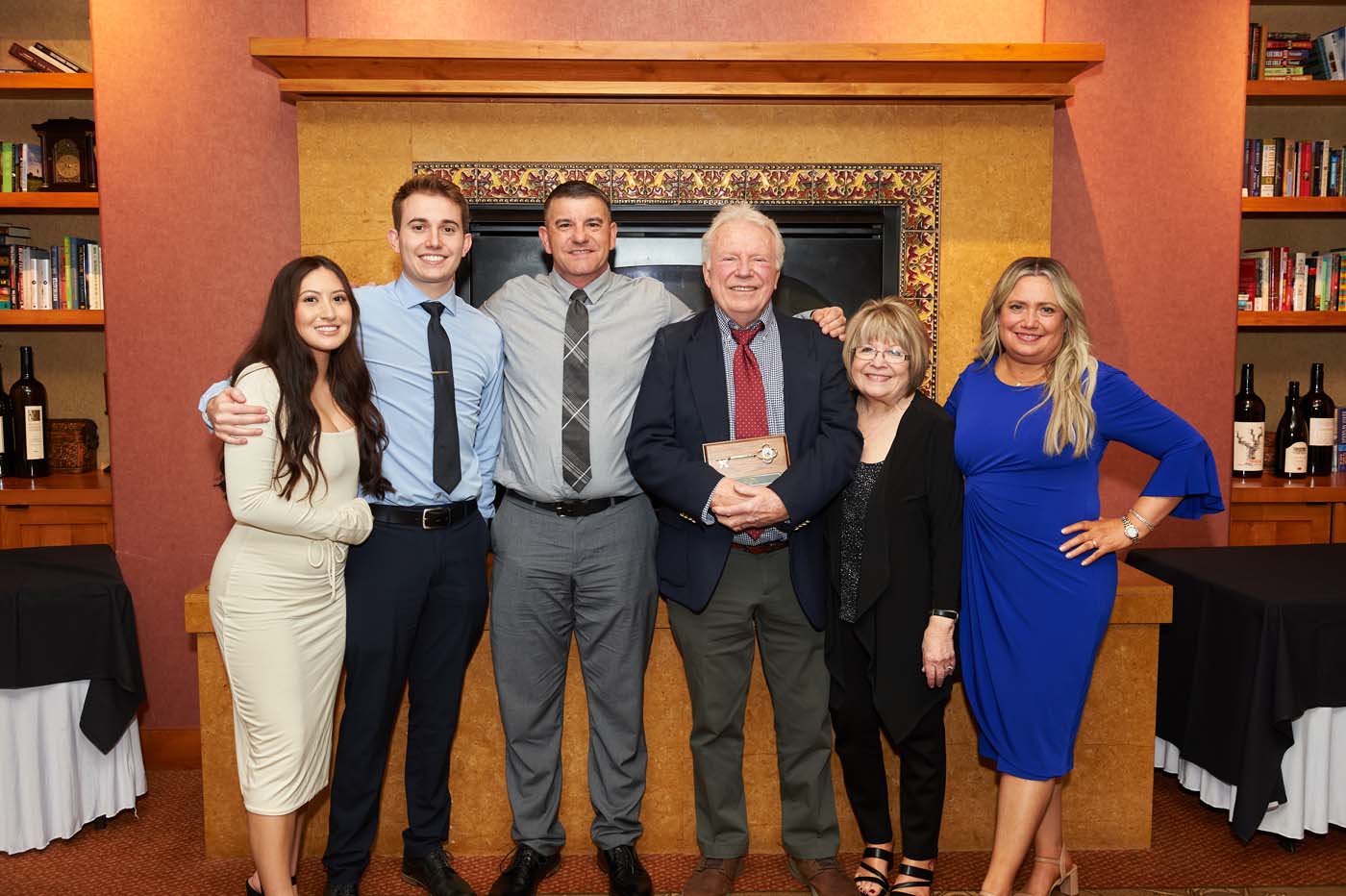 A group of people posing, with one man holding a plaque
