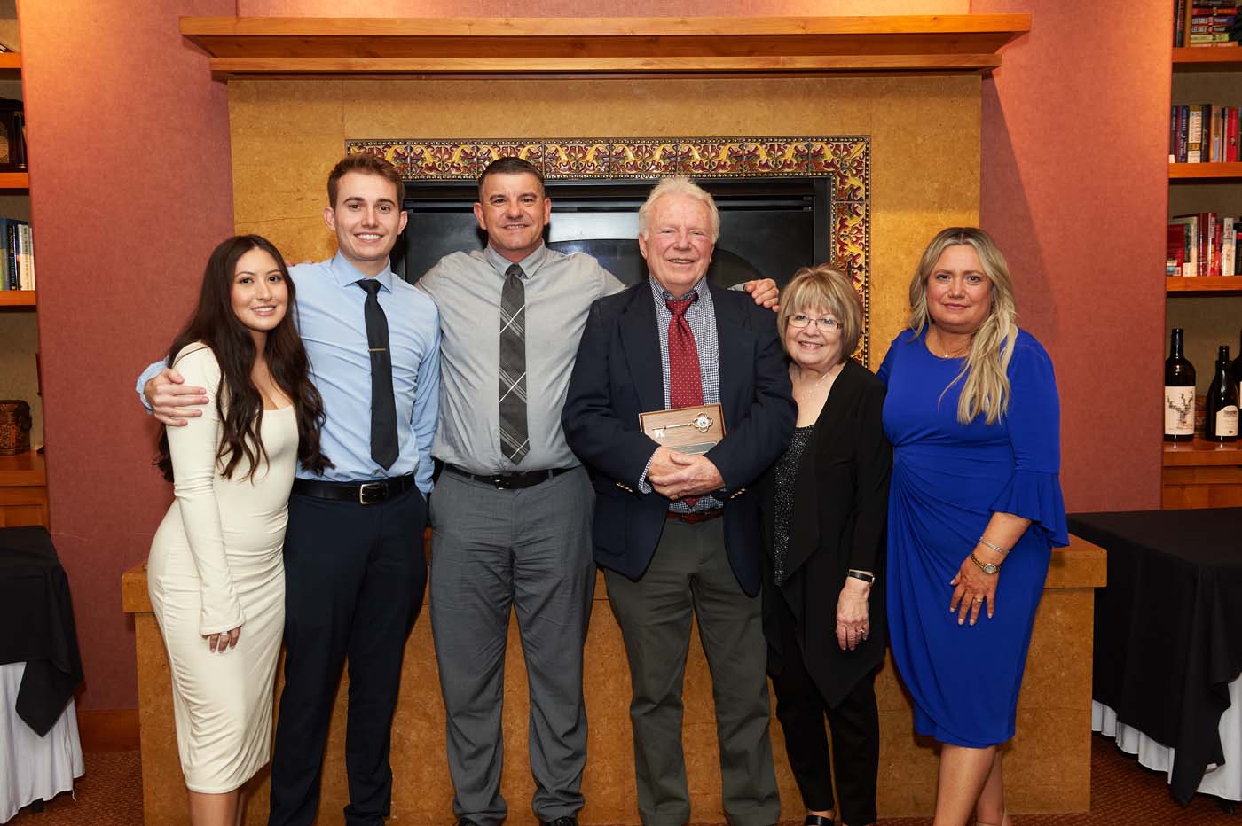 A group of people posing, with one man holding a plaque