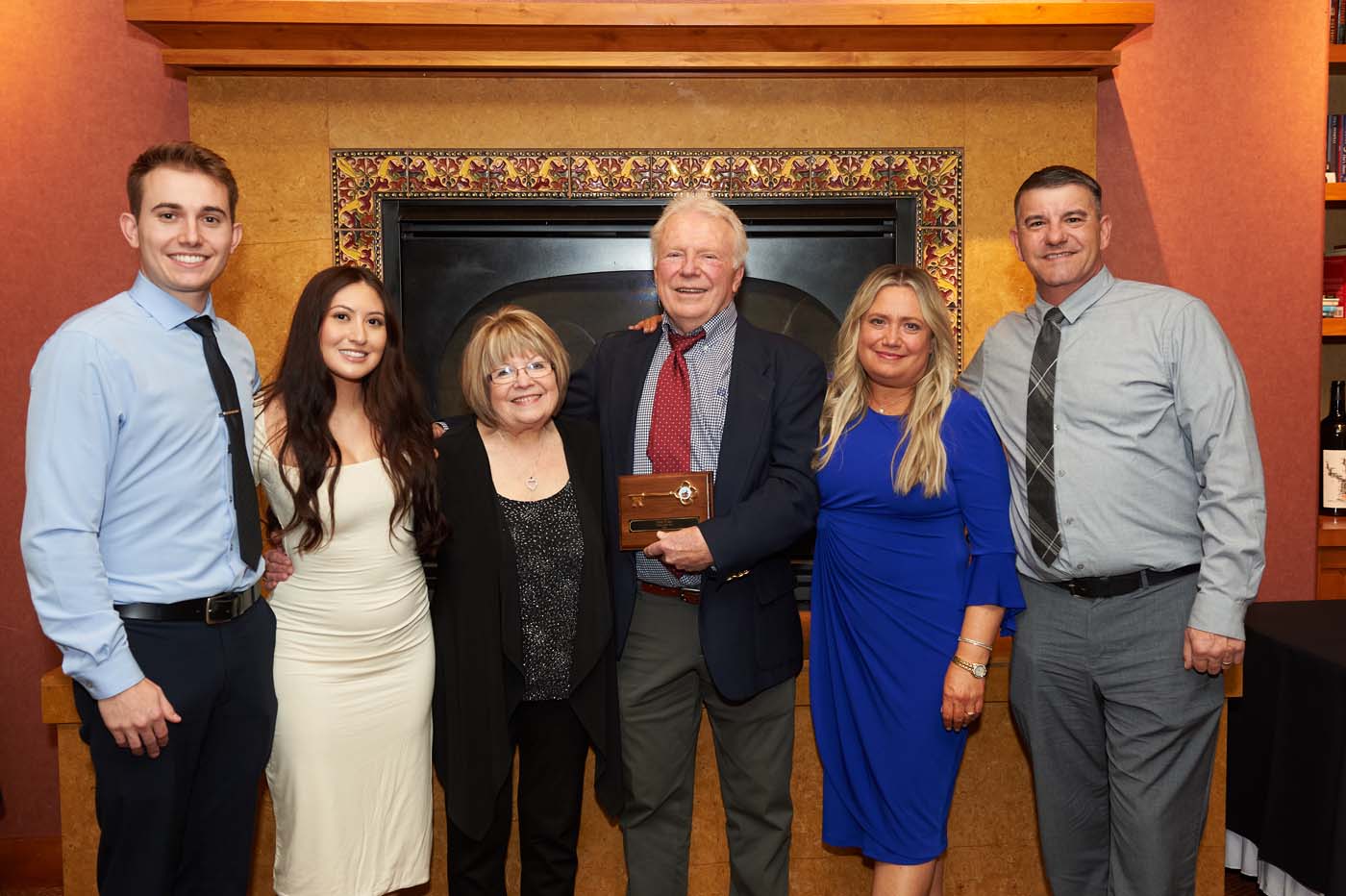 A group of people posing, with one man holding a plaque
