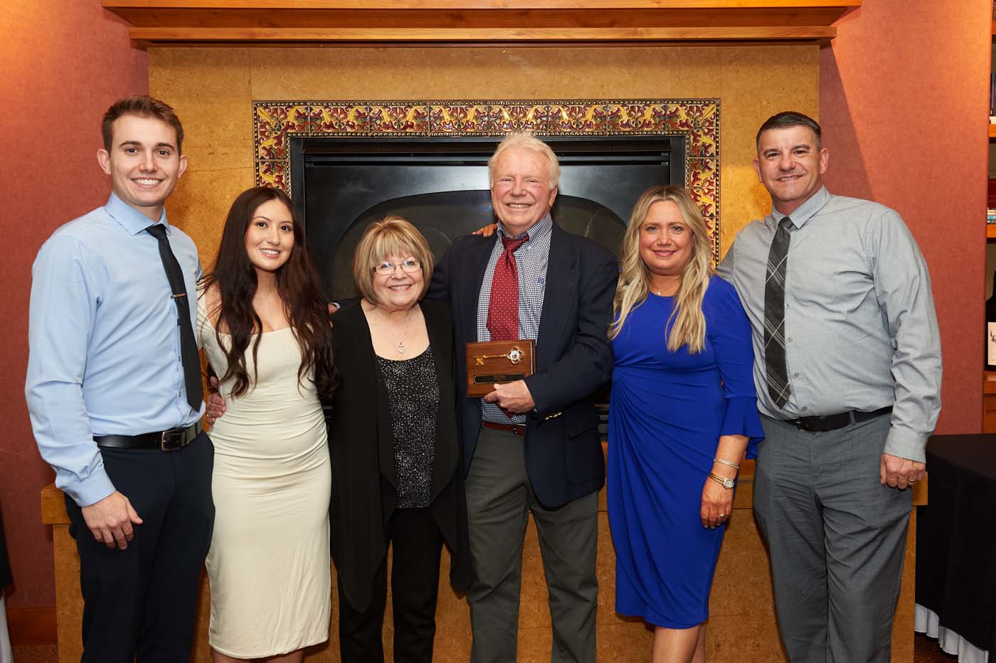 A group of people posing, with one man holding a plaque